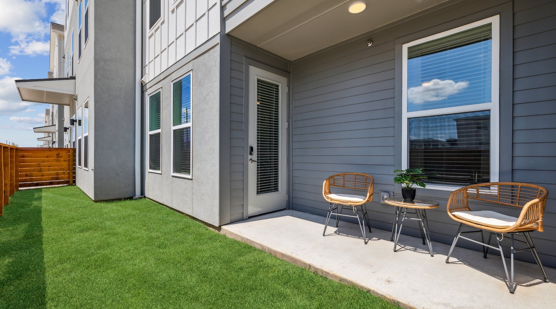 Spacious balconies a patio area with grass, two chairs and a table